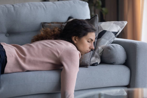 joven cansada durmiendo en el sofá en casa - agotamiento fotografías e imágenes de stock