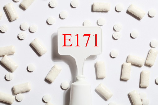 Titanium dioxide, E171, dangerous additive concept. gum, pills, toothpaste or cream and sign with E171 on white background. copy space