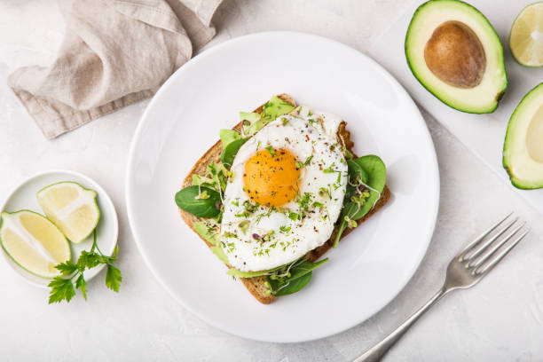 toast with avocado, spinach and fried egg toast with avocado, spinach and fried egg, top view toasted bread stock pictures, royalty-free photos & images