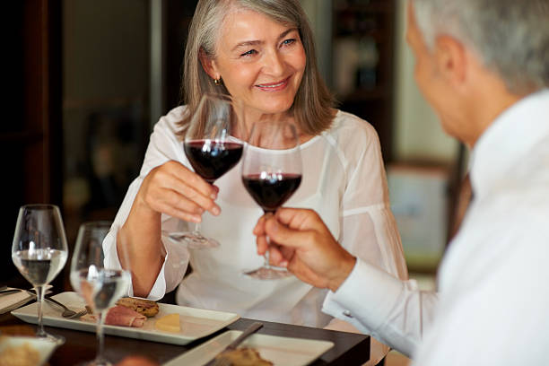 Toasting to their relationship Elderly woman toasting wine with her husband at a smart restaurant fine dining stock pictures, royalty-free photos & images