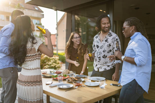 Toasting with happy friends on a hot summer evening in a new house. Internationally diverse nationalities. stock photo