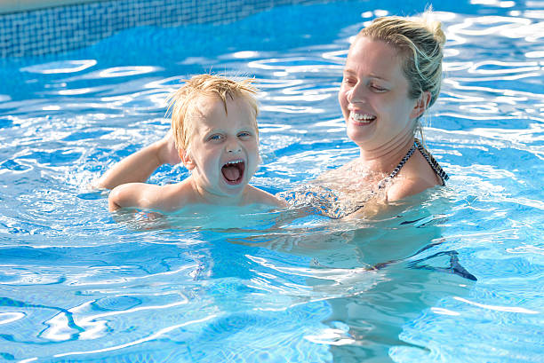 toddler and mother having great time in a swiming pool stock photo