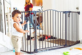 istock Toddler boy trapped in the living room by a baby gate for safety at home 1344322670
