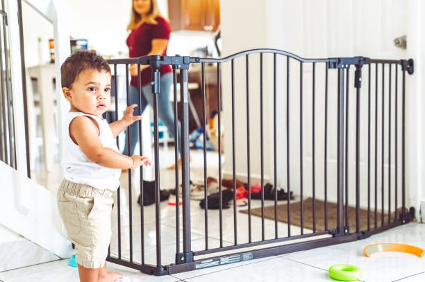 Toddler boy trapped in the living room by a baby gate for safety at home stock photo