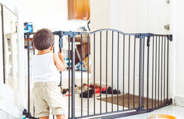 Toddler boy trapped in the living room by a baby gate for safety at home stock photo