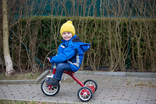 Toddler child, riding little tricycle in the park, wintertime