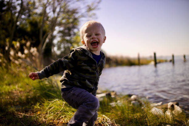 Toddler laughing by a river stock photo