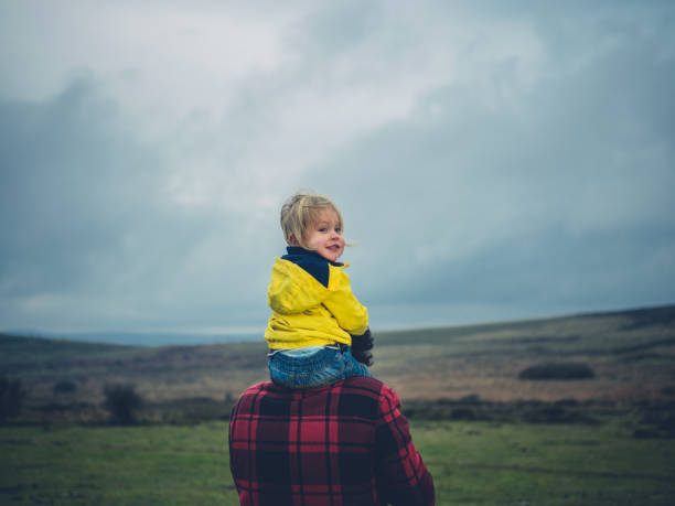 Toddler riding on father's shoulders on the moor A little toddler is riding on his father's shoulders on the moor moor photos stock pictures, royalty-free photos & images