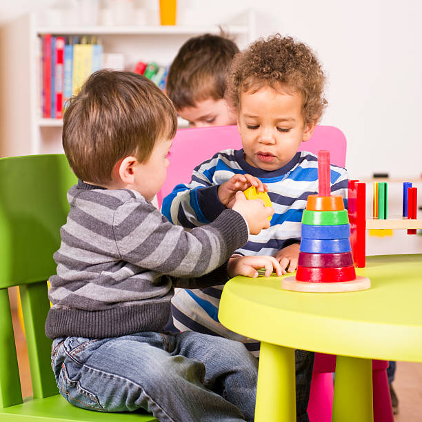 Toddlers helping and sharing in the playroom stock photo