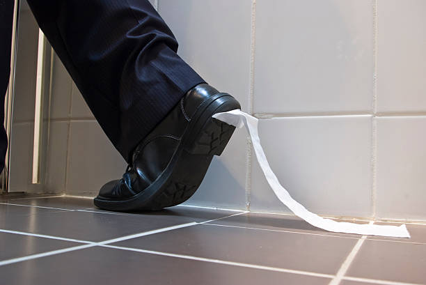 Toilet Paper stuck to sole of dress shoe stock photo
