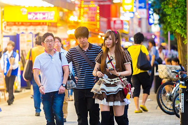 Tokyo Akihabara French Maid Outfit Cafe Customers Tokyo, Japan - July 31, 2015: Young Japanese girl in French maid outfit attracting male customers on the sidewalk to enter Japanese maid cafe restaurant in Akihabara french maid outfit stock pictures, royalty-free photos & images