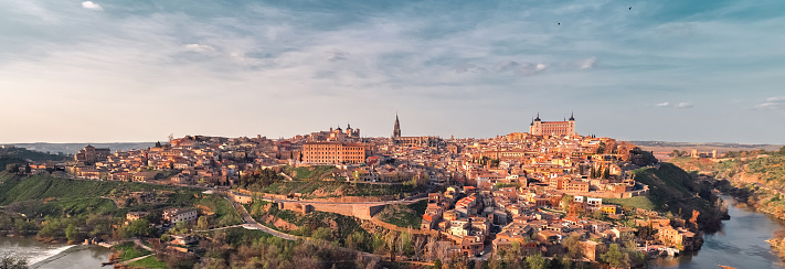 Distant panoramic view Toledo historical picturesque city surrounded by Tagus river located on hilltop, cloudy sky sunny day. Castilla–La Mancha. Europe. Travel destinations, landmark concept. Spain