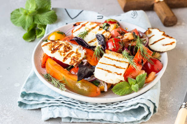 Tomato, baked pepper and onion salad with grilled haloumi cheese (halloumi). Keto diet, healthy food. stock photo