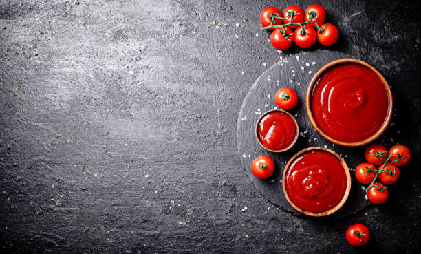 Tomato sauce in a wooden plate on a stone board with salt. stock photo