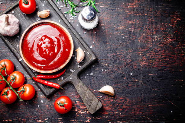 Tomato sauce on a cutting board with red pepper, garlic and rosemary. stock photo