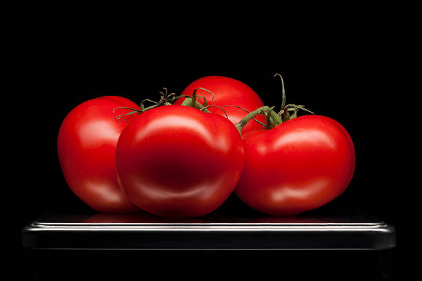 Four red ripe tomatoes on tray with luxury black background. Clean...