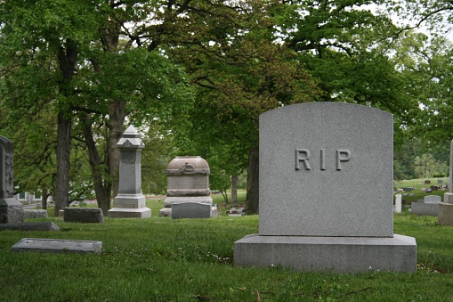 Cemetary with tombstone reading RIP - rest in peace.