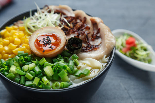 tonkotsu ramen, japanese noodle soup with pork belly, corn, spring onion and nitamago on top stock photo