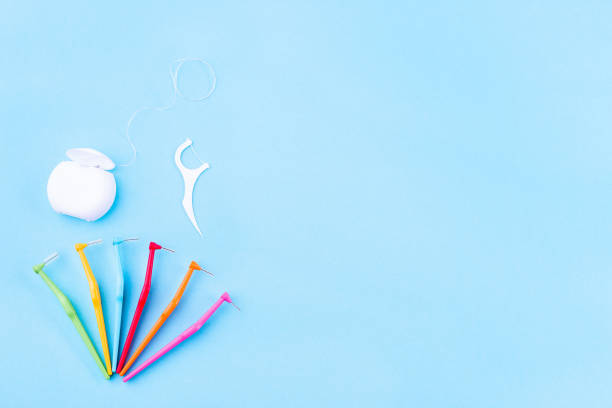 Tooth care and oral hygiene products, dental floss and interdental brush angles on blue, copy space stock photo