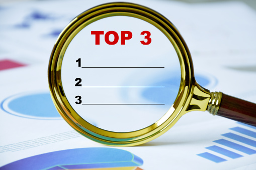 Top 3 word business concept. Top 3 ranking in the magnifying glass with business documents
