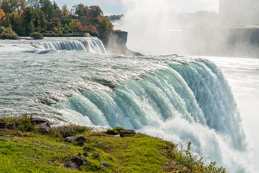 Top of American Falls, a part of Niagara Falls, with a powerful stream of falling water. Sunny autumn day