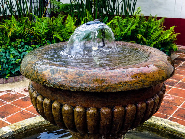 Top of antique water fountain with garden in background Top of antique water fountain with garden in background building feature stock pictures, royalty-free photos & images