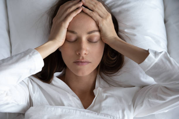 top view depressed woman suffering from headache, lying in bed - migraine imagens e fotografias de stock