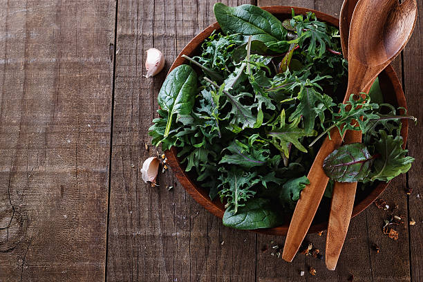 Top view image of leafy green mix over wooden background Top view image of leafy green mix of kale, spinach, baby beetroot leaves in a wooden bowl over rustic wooden background. Copy space, close up leaf vegetable stock pictures, royalty-free photos & images
