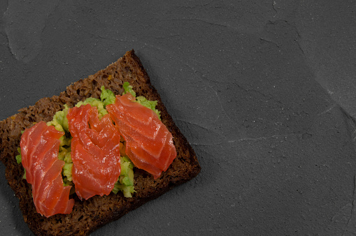 Top view multi-cereal bread toast with smash avocado and red fish salmon on concrete