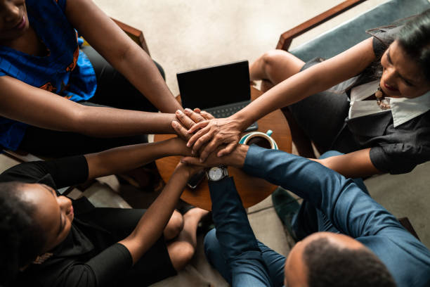 Top view of black african business team with hands stacked together in unity and trust.  over achiever stock pictures, royalty-free photos & images