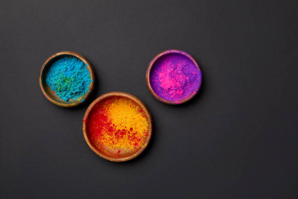 top view of colorful holi powder in bowls on grey surface top view of colorful holi powder in bowls on grey surface holi photos stock pictures, royalty-free photos & images