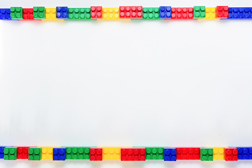 Top view of colorful plastic toy construction bricks frame isolated on white background with copy space, flat lay