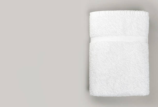 Top view of folded clean white bathroom towel on gray background with copy space Top view of Fluffy clean white bathroom towel on gray background with copy space towel stock pictures, royalty-free photos & images