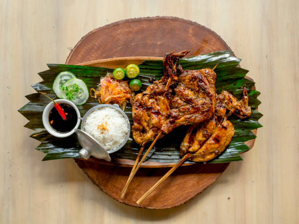 Top view of juicy Chicken Inato with a serving of garlic rice and atchara. Placed on a circular wooden tray. A popular grilled dish in Cebu. stock photo