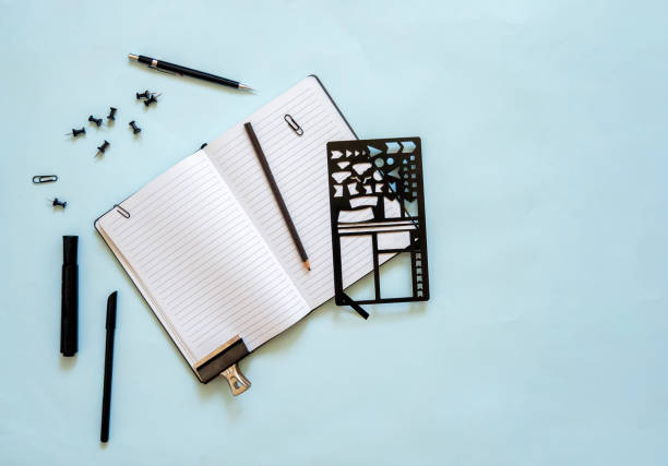 Top view of lined notebook open with black stationery and a bullet journal stencil stock photo