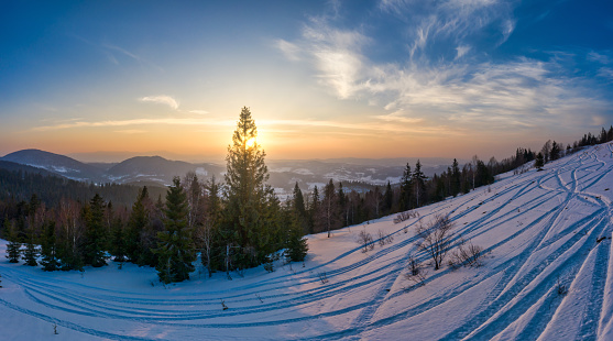 Top view of a beautiful mesmerizing view of the ski slope with ski trails located in the mountains on a sunny winter frosty evening. Vacation and tourism concept in winter. Copyspace