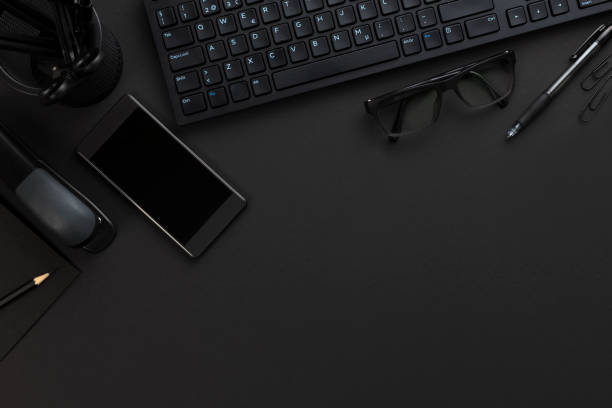 Top view of pitch black office desk with computer and supplies stock photo