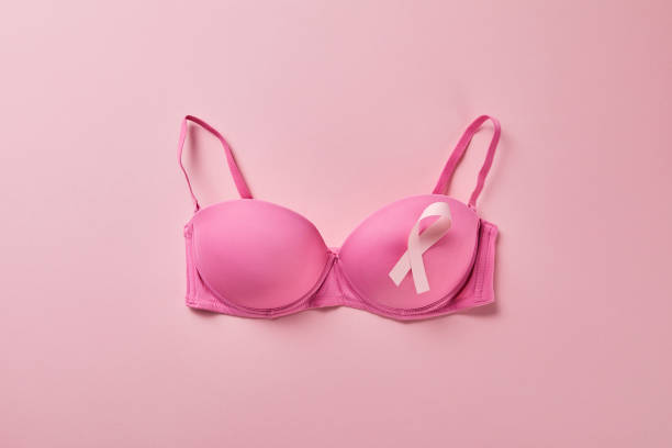 top view of ribbon on brassiere on pink background, breast cancer concept top view of ribbon on brassiere on pink background, breast cancer concept bra stock pictures, royalty-free photos & images