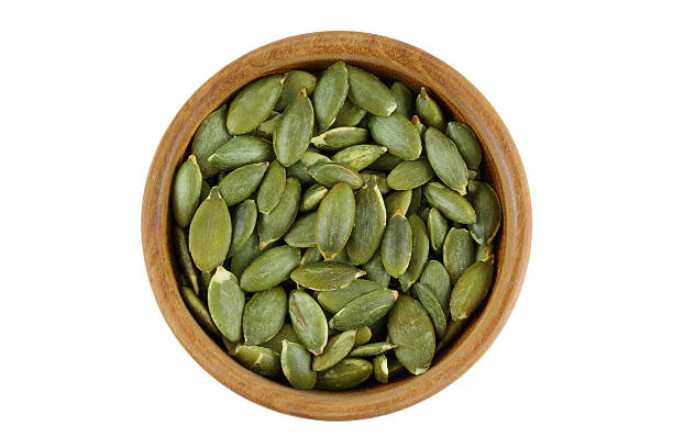 Top view of roasted pumpkin seeds in wooden bowl stock photo