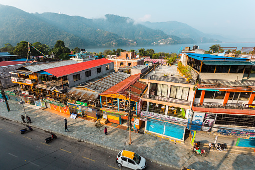 Pokhara, Nepal - November 11, 2018: People walking down the street in the early morning. Top view of the Phewa lake and Pokhara streets.
