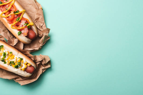 top view of two tasty hot dogs in paper on blue top view of two tasty hot dogs in paper on blue hot dog stock pictures, royalty-free photos & images