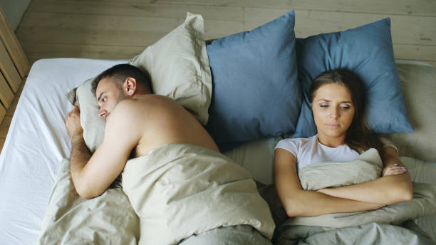 Top view of upset lying sleepless couple in bed offended because of quarrel stock photo