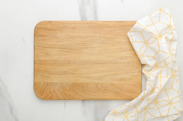 Top view of woden cutting board and white napkin on the white marble table.Empty space Top view of wooden cutting board, wooden spoons, knife and napkin on the white marble table.Empty space cutting board stock pictures, royalty-free photos & images