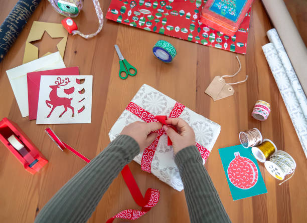 Top view of woman hand wrapping presents and making a bow stock photo