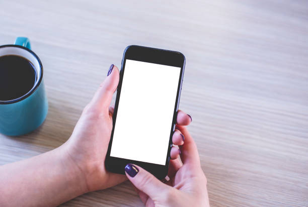 Top view of woman hands holding phone with blank white screen for mockup design stock photo