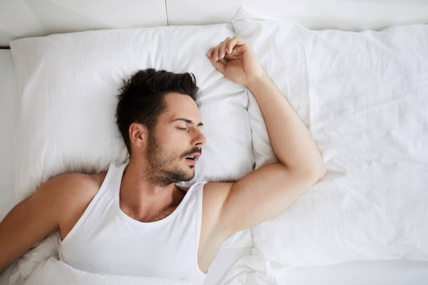 Top view of young attractive man sleeping with mouth open Top view of young attractive man sleeping with mouth open man sleeping in bed top view stock pictures, royalty-free photos & images