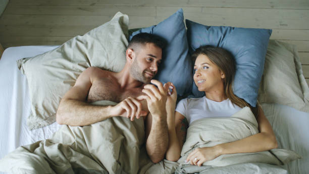 Top view of young couple lying in bed and talking each other smiling stock photo