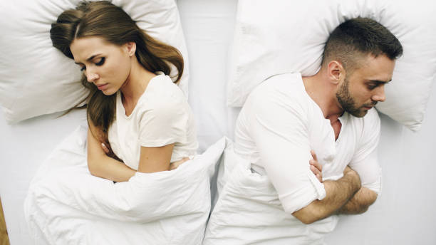 Top view of young upset couple lying in bed have problems after quarrel and angry each other at home stock photo