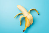 istock Top view photo of one peeled ripe banana in the middle on isolated pastel blue background 1329702028