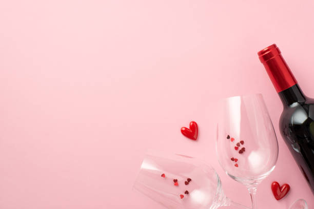 Top view photo of valentine's day decorations small hearts between two wineglasses with confetti and wine bottle on isolated pastel pink background with empty space Top view photo of valentine's day decorations small hearts between two wineglasses with confetti and wine bottle on isolated pastel pink background with empty space happy birthday wine bottle stock pictures, royalty-free photos & images